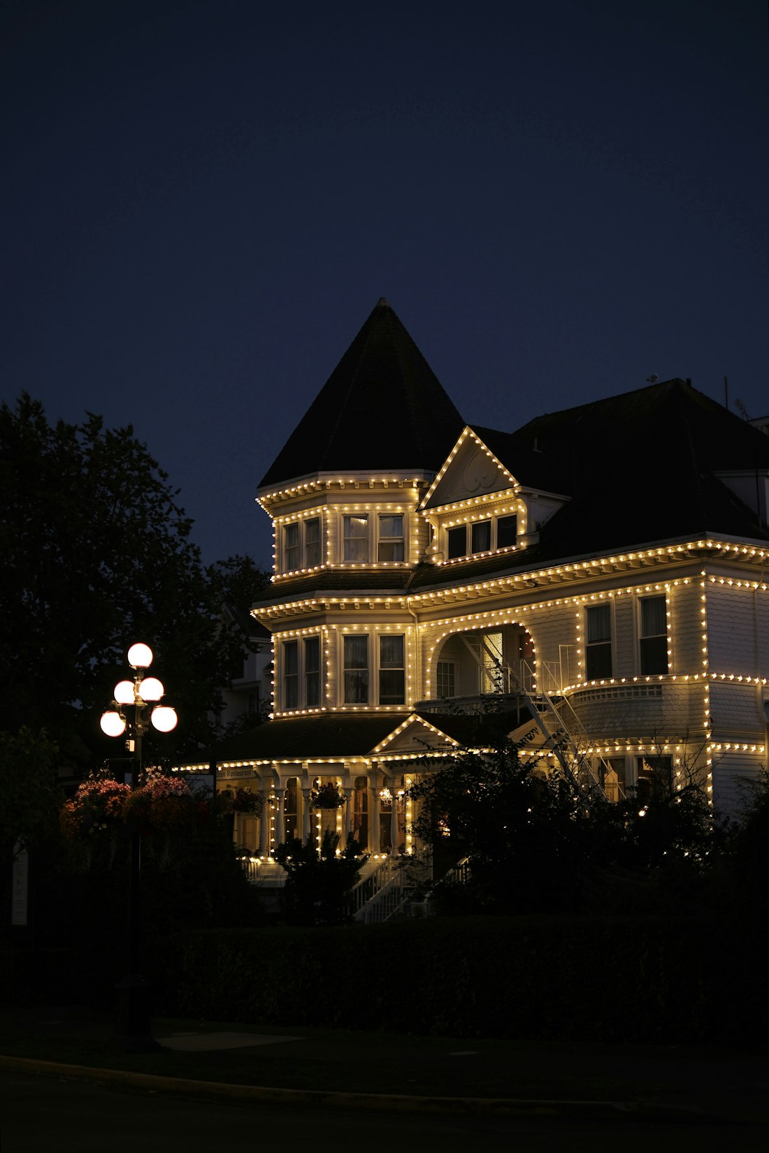Home with warm white lights along every roofline and eave at dusk